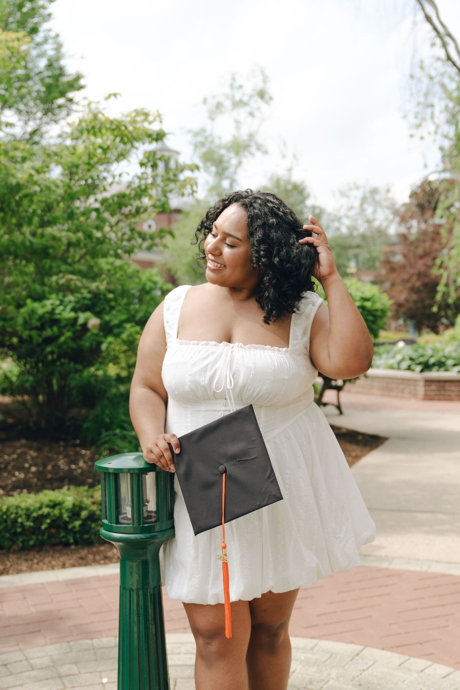 Joyful bride in flowing white dress holds fabric against bright blue sky.