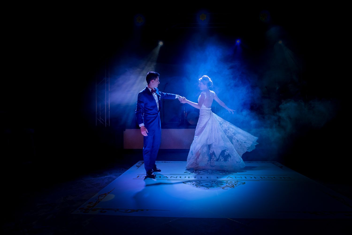 Dramatic dance scene with couple illuminated by blue stage lighting.