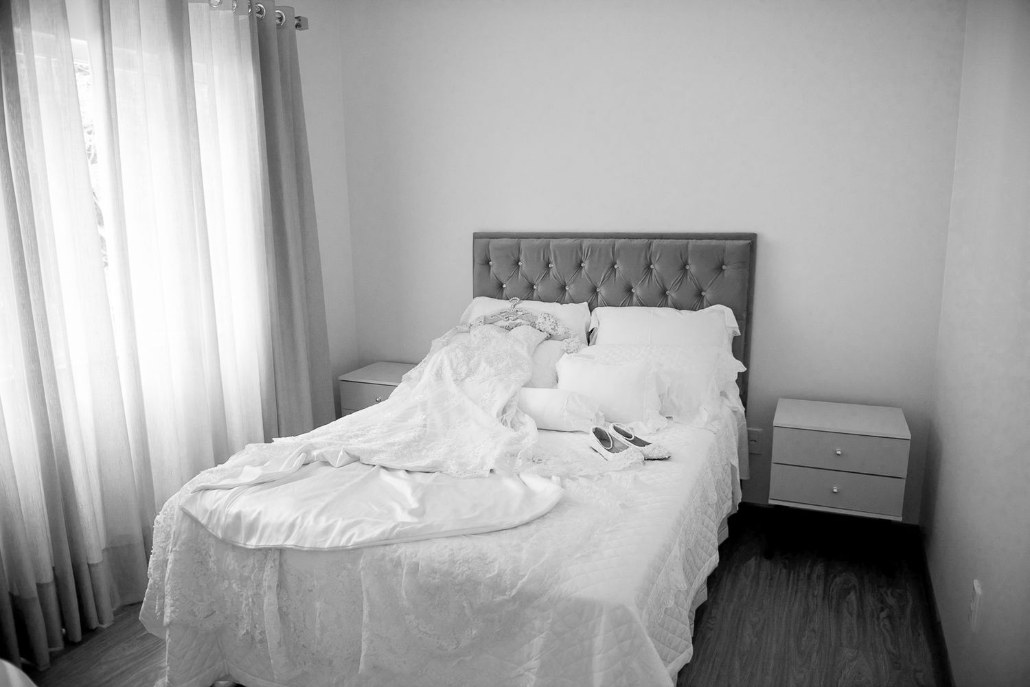 Modern bedroom interior with tufted headboard and white bedding in natural light.