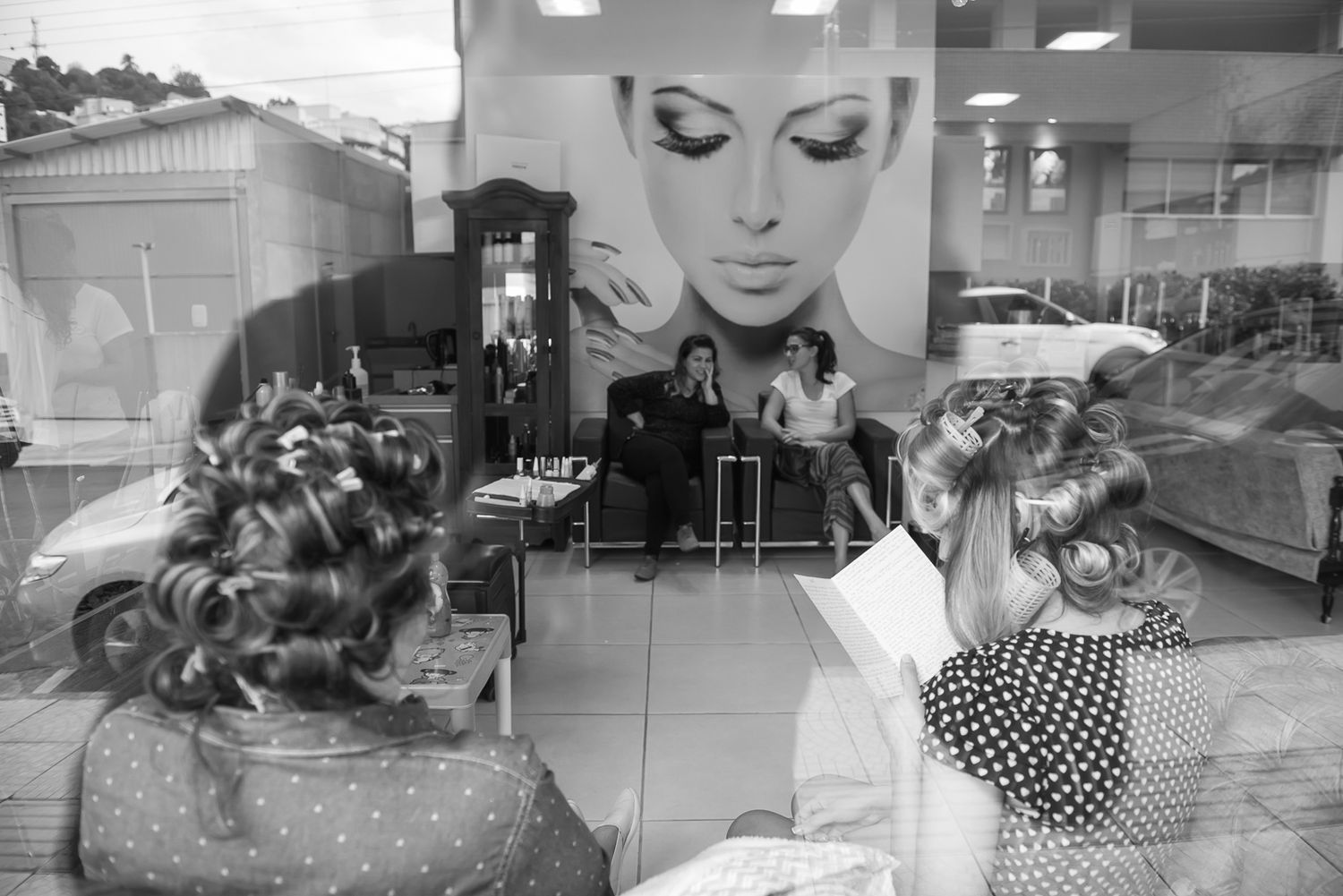 Reflection in salon window showing vintage-style hair curlers and beauty salon decor.
