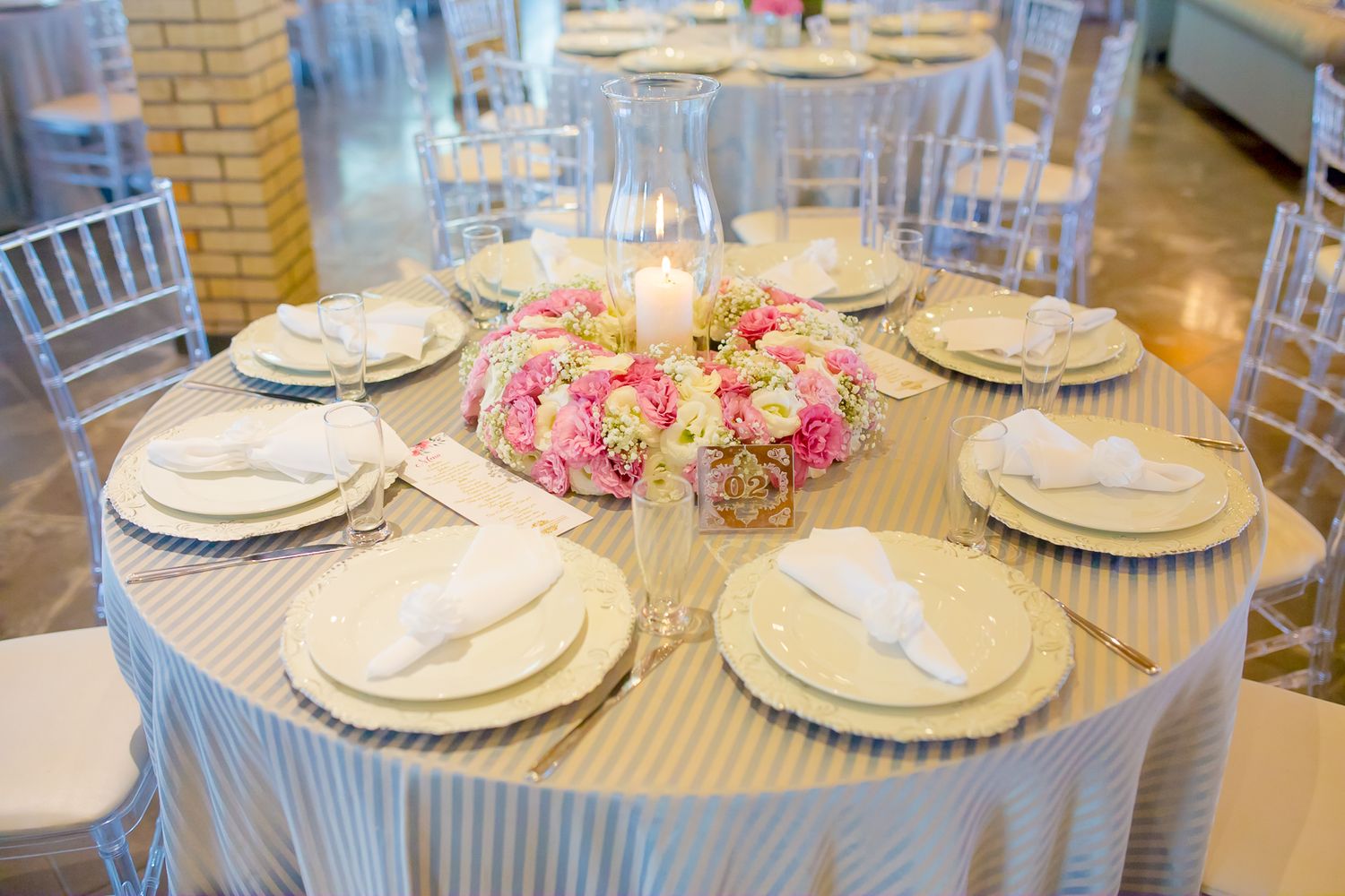 Round dining table with white linens, pink floral centerpiece and elegant place settings.