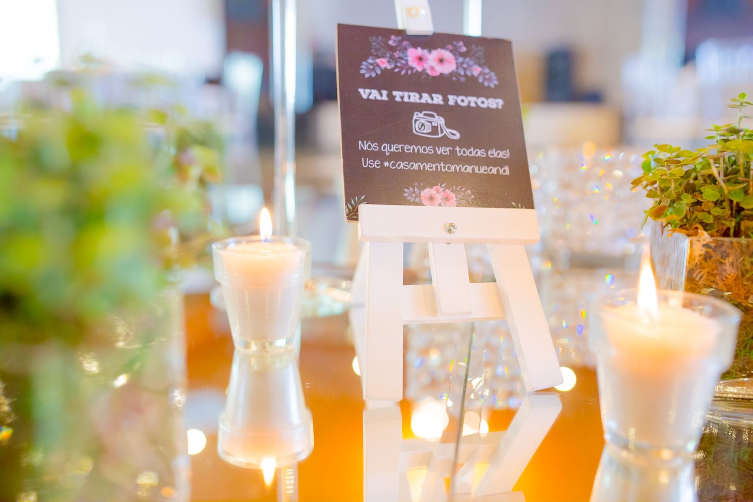 Lit candles and event signage on an elegant crystal table setting.