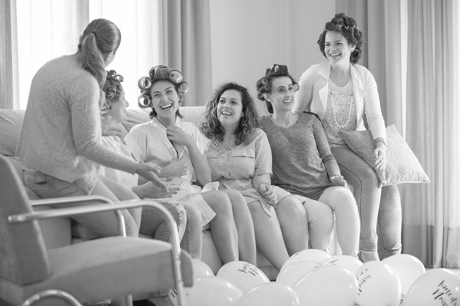 Casual gathering in bright room with people seated on couch sharing moments.