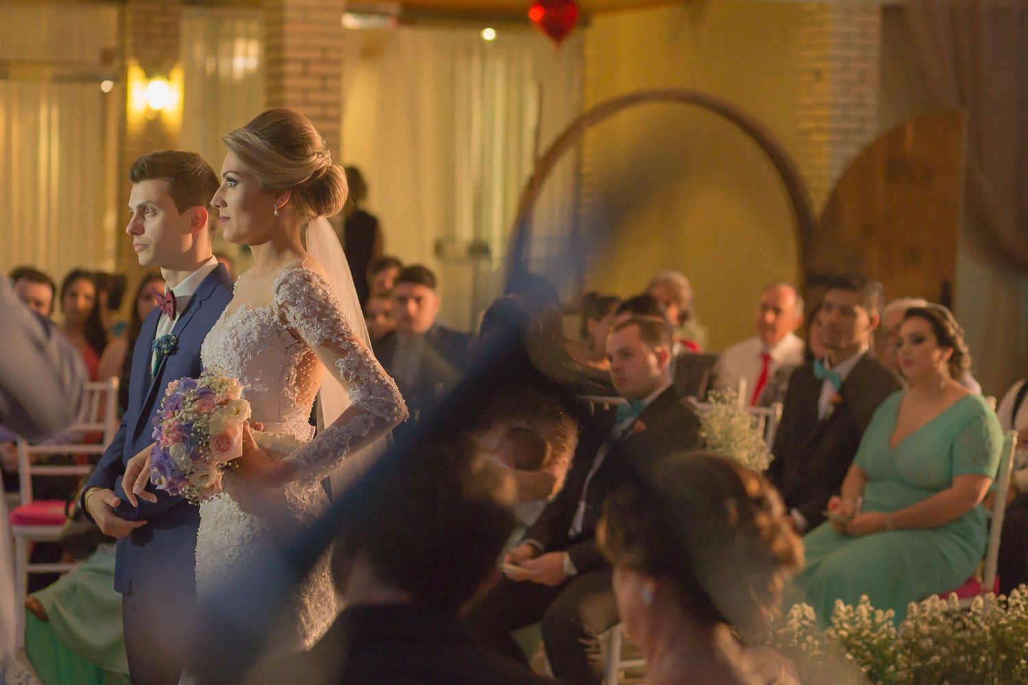 Couple exchanges vows during evening wedding ceremony in an elegantly decorated indoor venue.