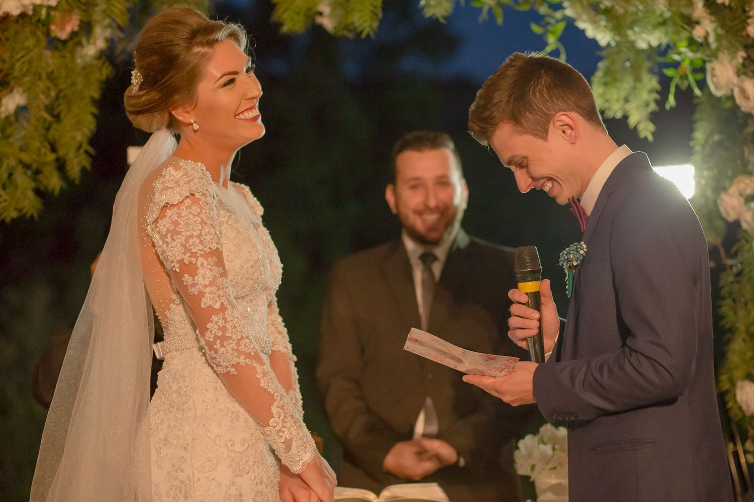 Evening wedding ceremony under leaf-covered arch with romantic lighting.