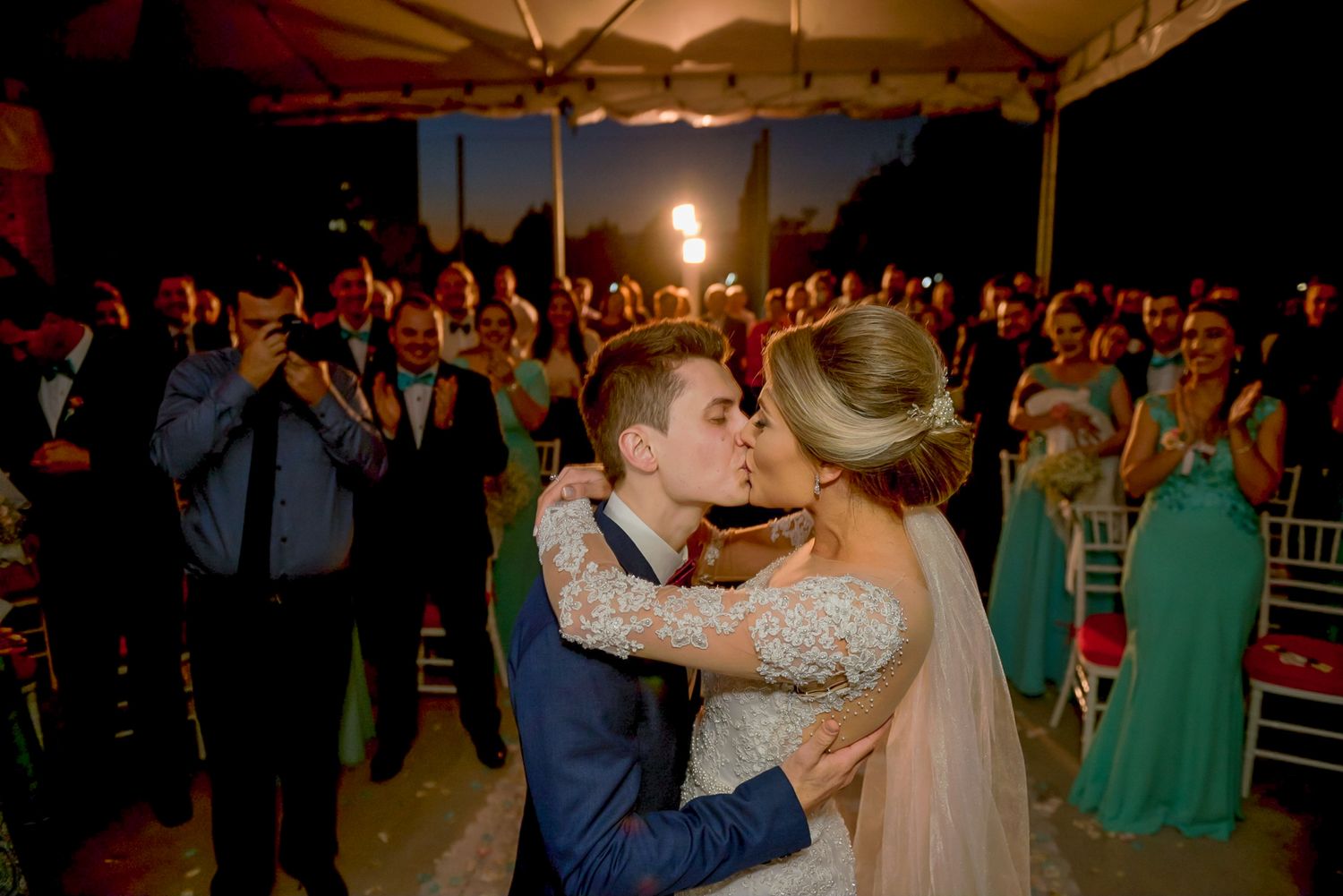 Romantic first dance at wedding reception under tent with warm lighting.