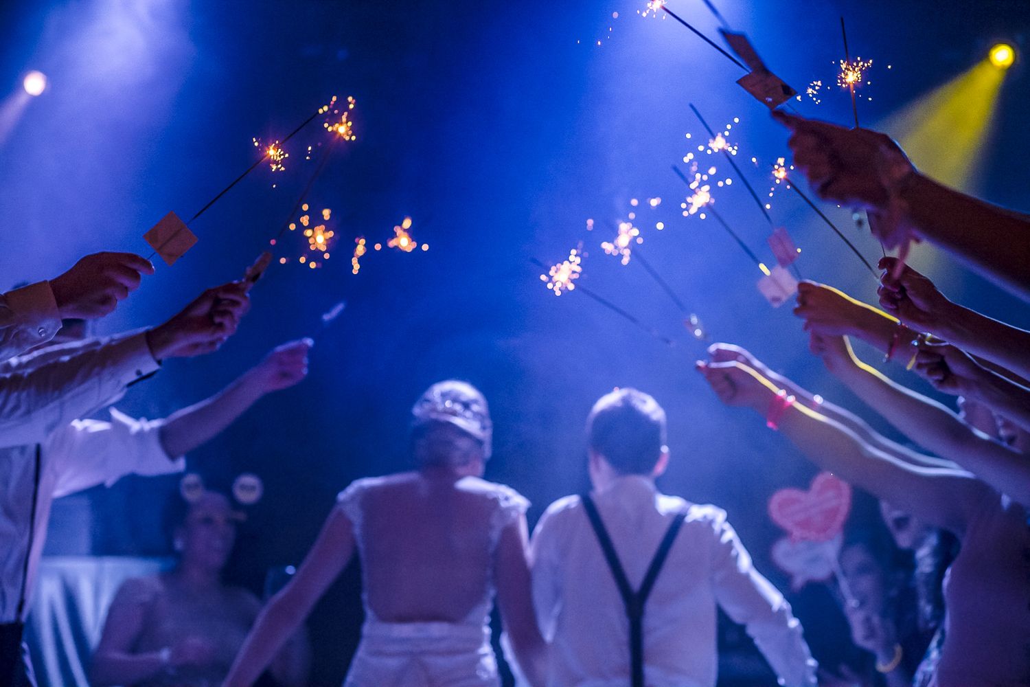 Wedding guests hold sparklers forming tunnel for celebration.