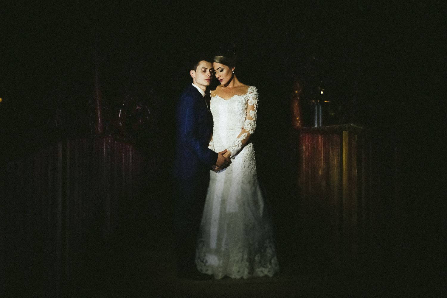 Intimate wedding couple portrait in dramatic dark lighting.
