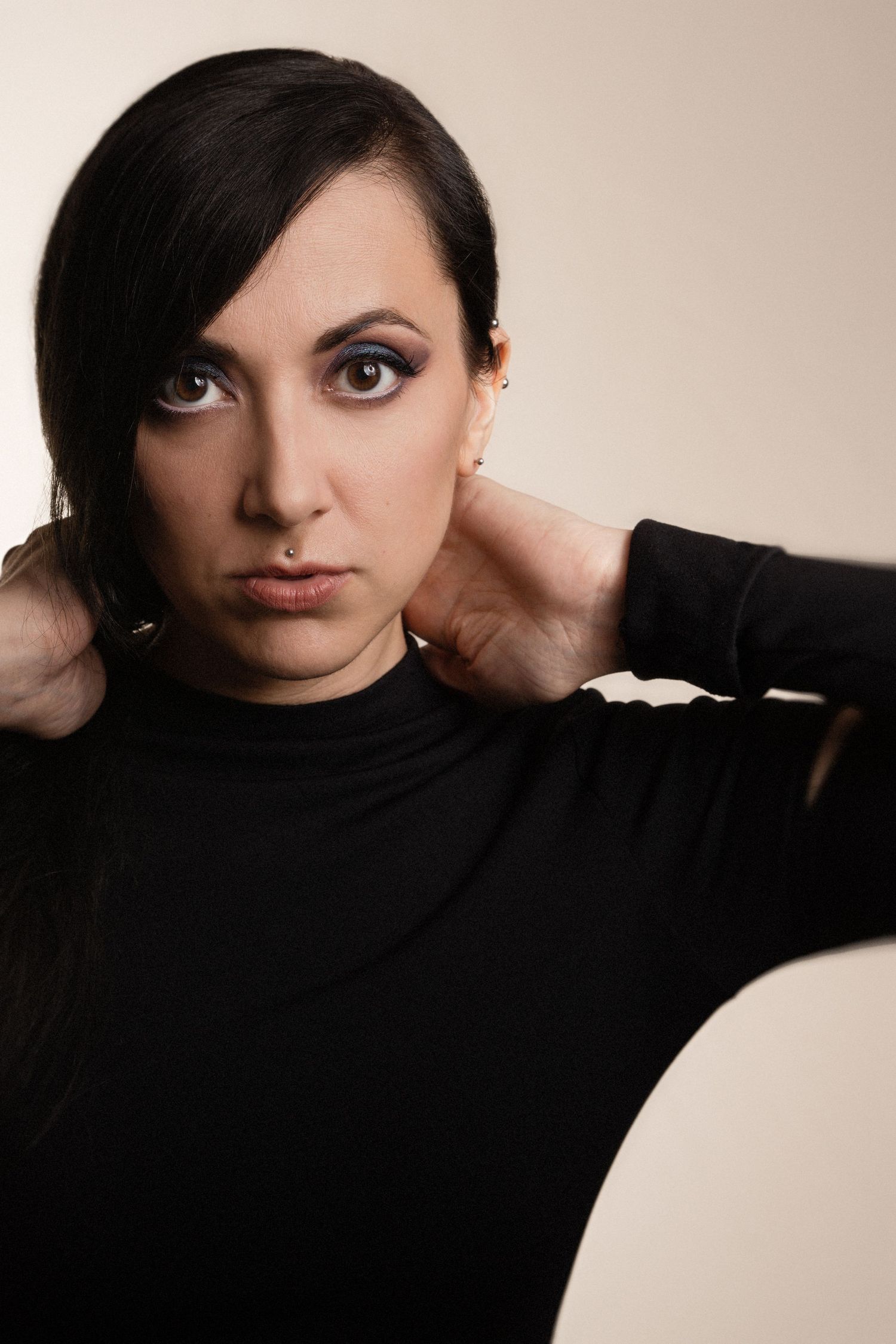 Artistic studio portrait shot against neutral background with dramatic pose.