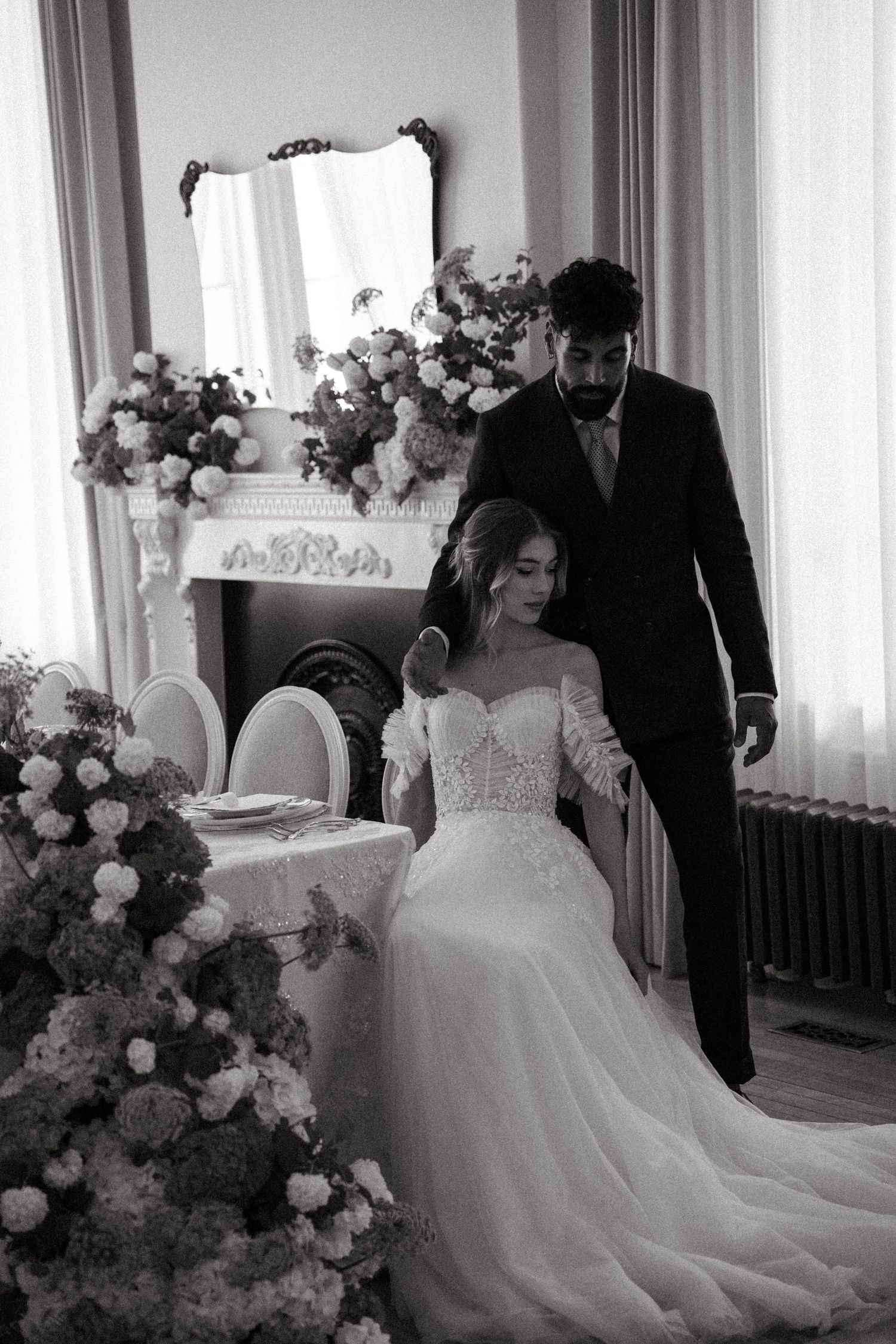 Black and white wedding reception photo with elegant cake and decorative floral arrangements.