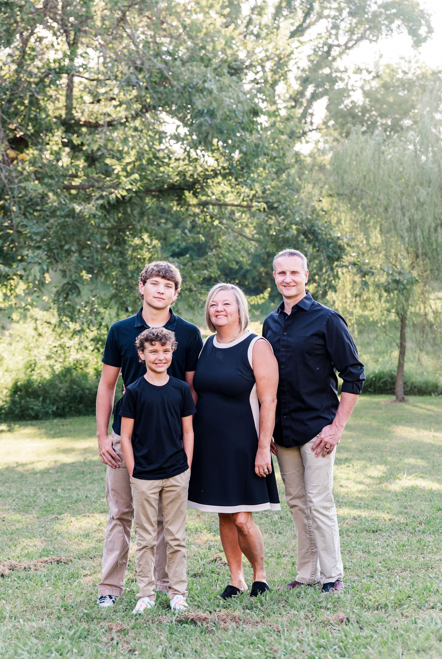 Family portraits with parents and 2 sons standing in front of backlit trees in Kuttawa, Kentucky.