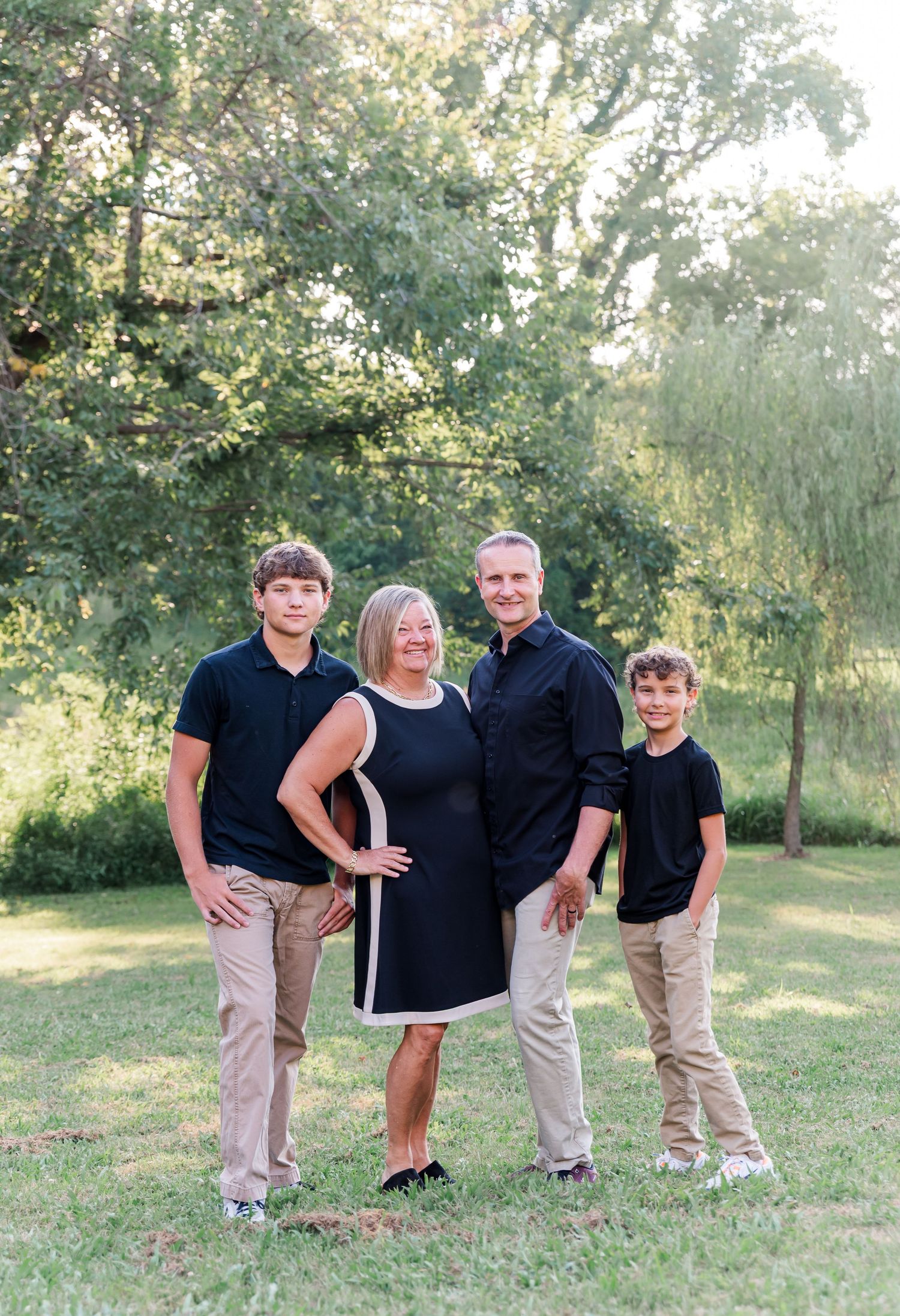 Family portraits with parents and 2 sons standing in front of backlit trees in Kuttawa, Kentucky