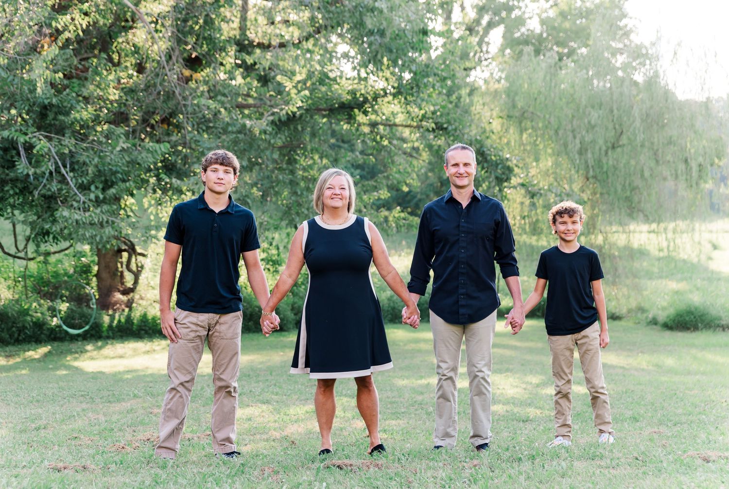 Family portraits with parents and 2 sons standing in front of backlit trees in Kuttawa, Kentucky.