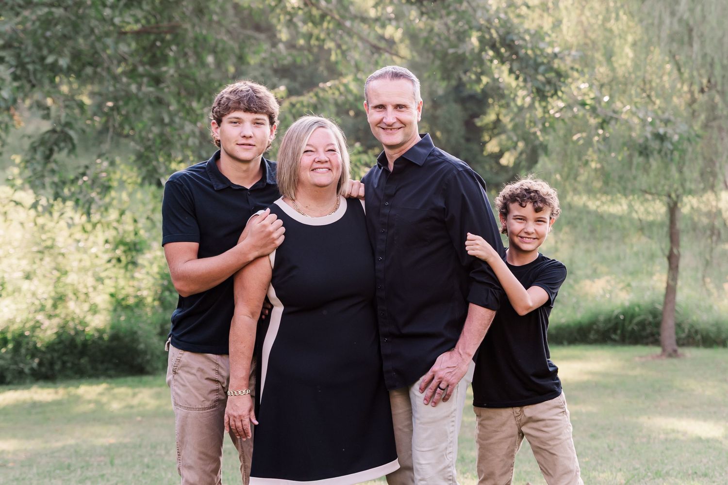 Mom, Dad, and 2 sons smiling for a portrait outside at sunset in Kuttawa, Kentucky.