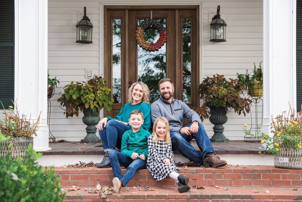 Fall family portraits with parents and 2 children sitting on the steps of a historic house in Eddyville, KY.
