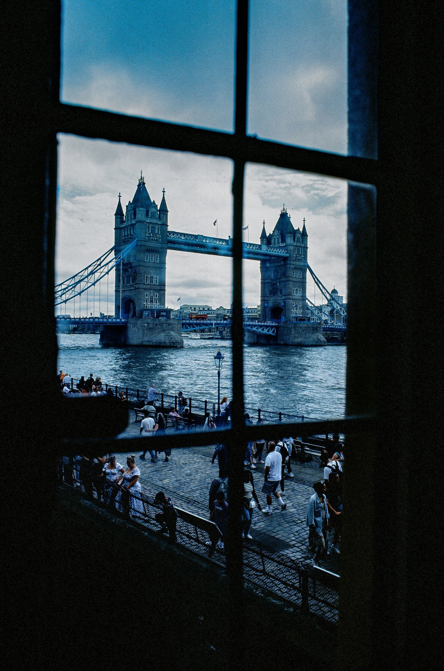 View of Tower Bridge through window on cloudy day in London.