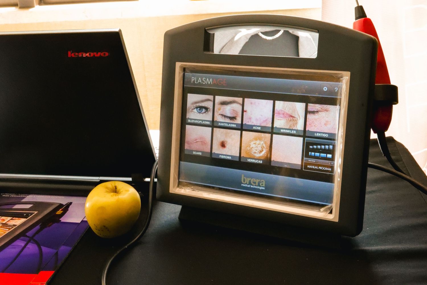 Medical aesthetic device with touchscreen displaying eyelid treatment options at a conference booth.