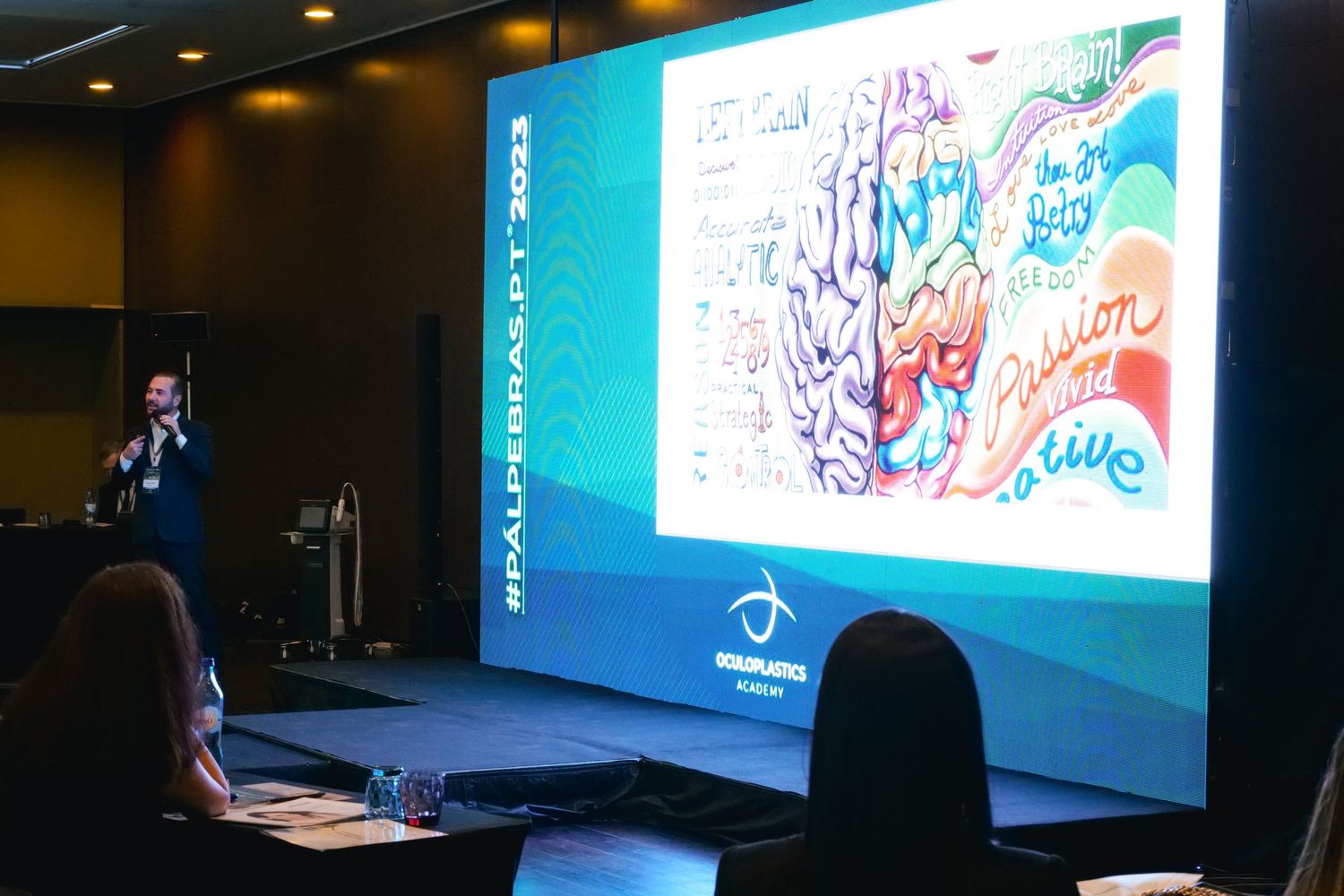 Speaker presenting a colorful brain illustration slide at a medical neuroscience conference in 2023.