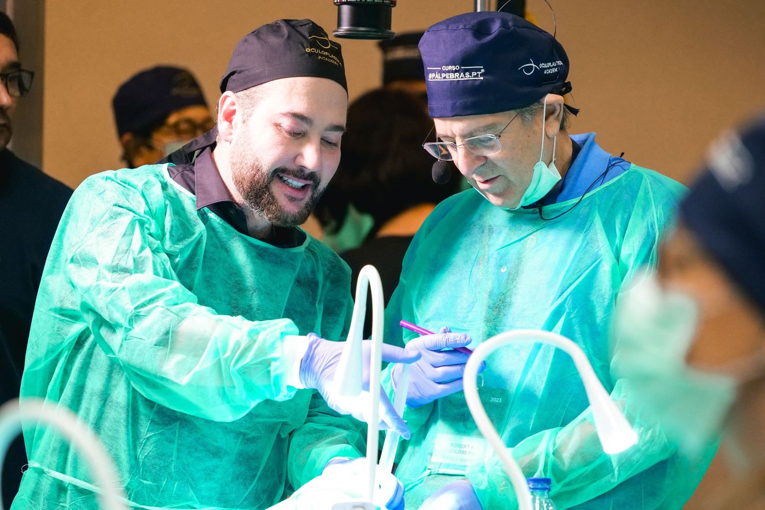 Two surgeons in green scrubs and gloves collaborate during a medical procedure in an operating room.