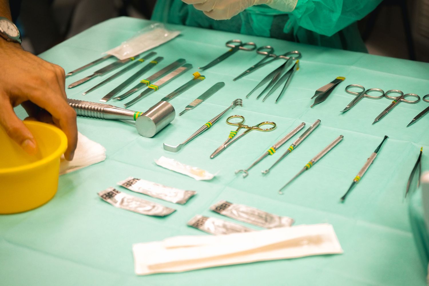 Sterile surgical instruments including scissors, clamps, and scalpels arranged on a green surgical drape.