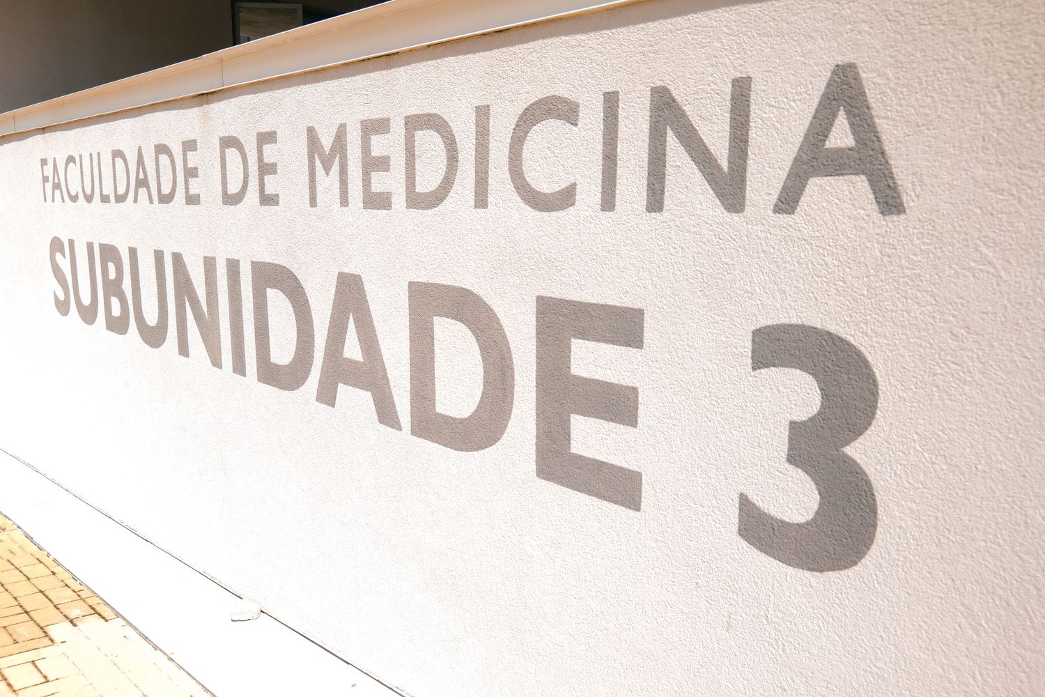 Exterior wall of Faculdade de Medicina Subunidade 3 medical faculty building with gray lettering.