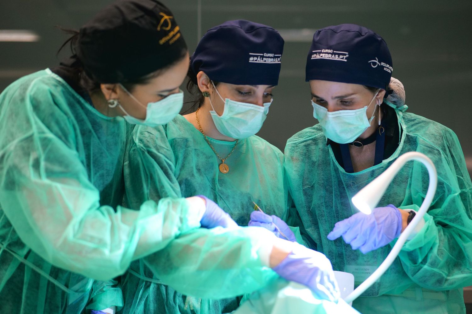 Three medical students in green scrubs and masks practice a surgical procedure during clinical training.