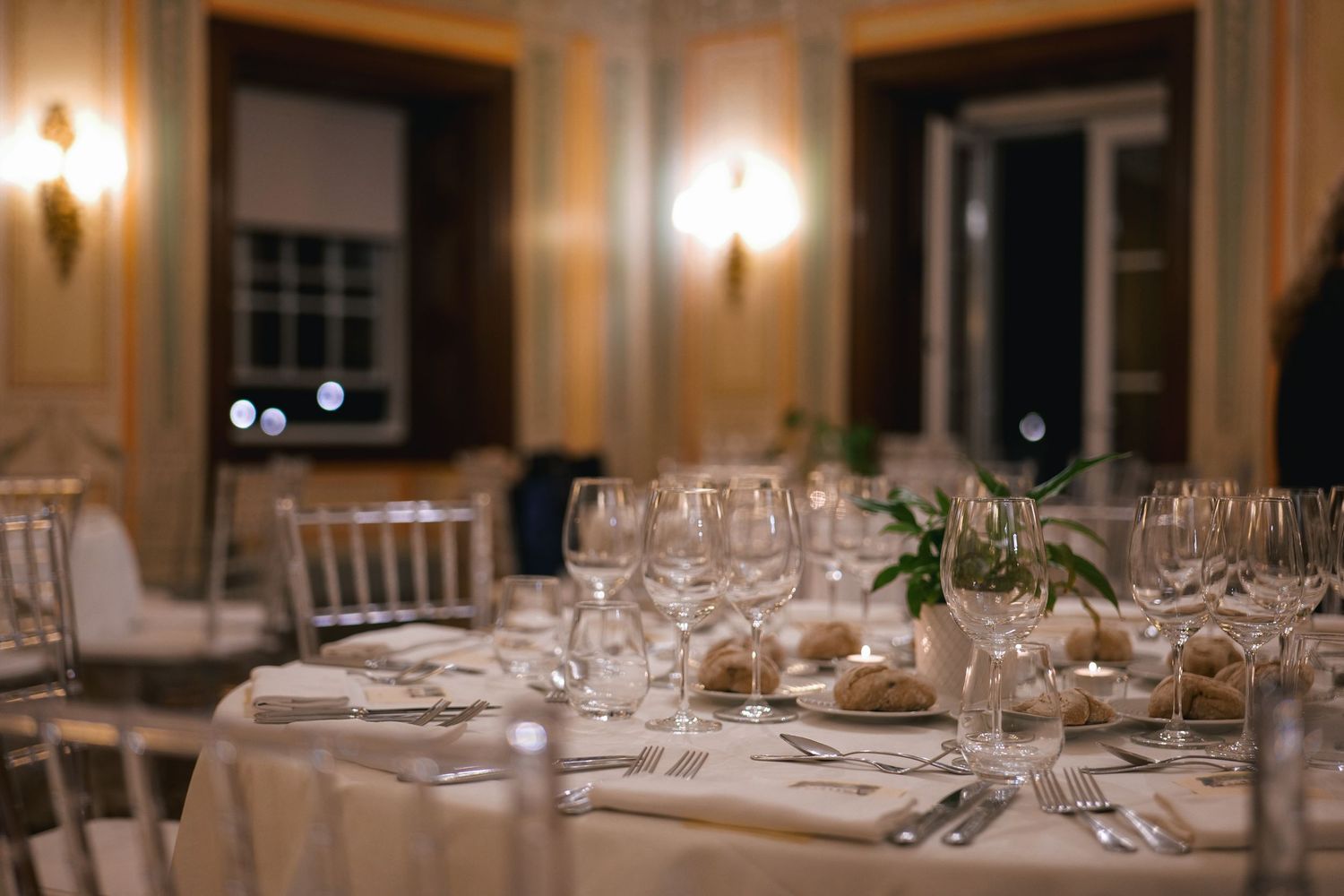 Elegant banquet table set with crystal wine glasses and fine dining silverware in a luxurious event hall.