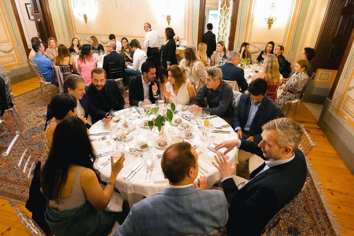 Guests socializing around a formal round dining table at an elegant indoor banquet event.