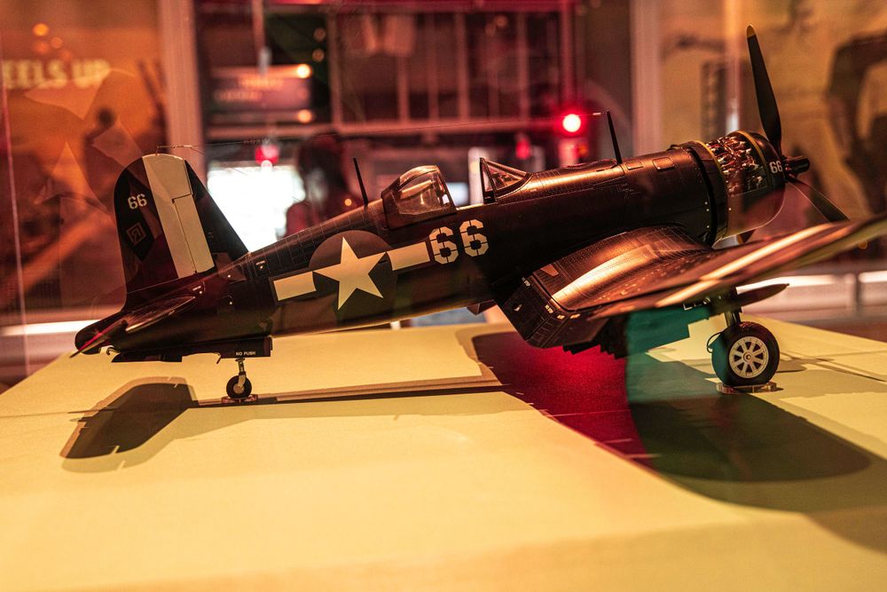Model of a World War II Corsair fighter plane displayed in museum lighting.