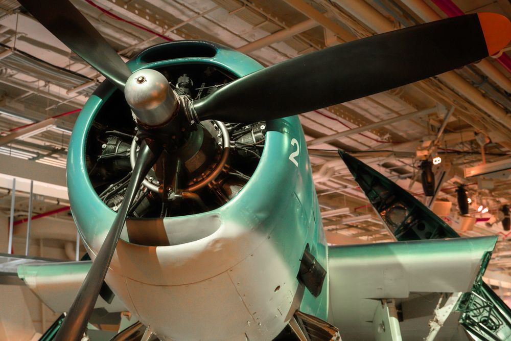 Close-up of vintage aircraft propeller and engine in mint green color at museum display.