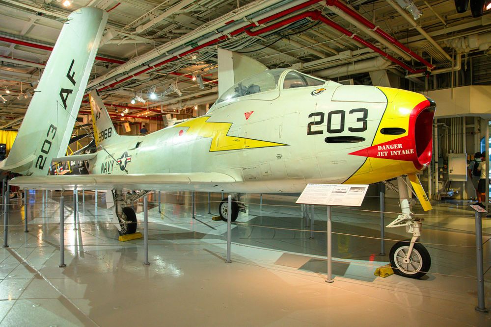 A vintage military aircraft with number 203 displayed in an indoor museum hangar.
