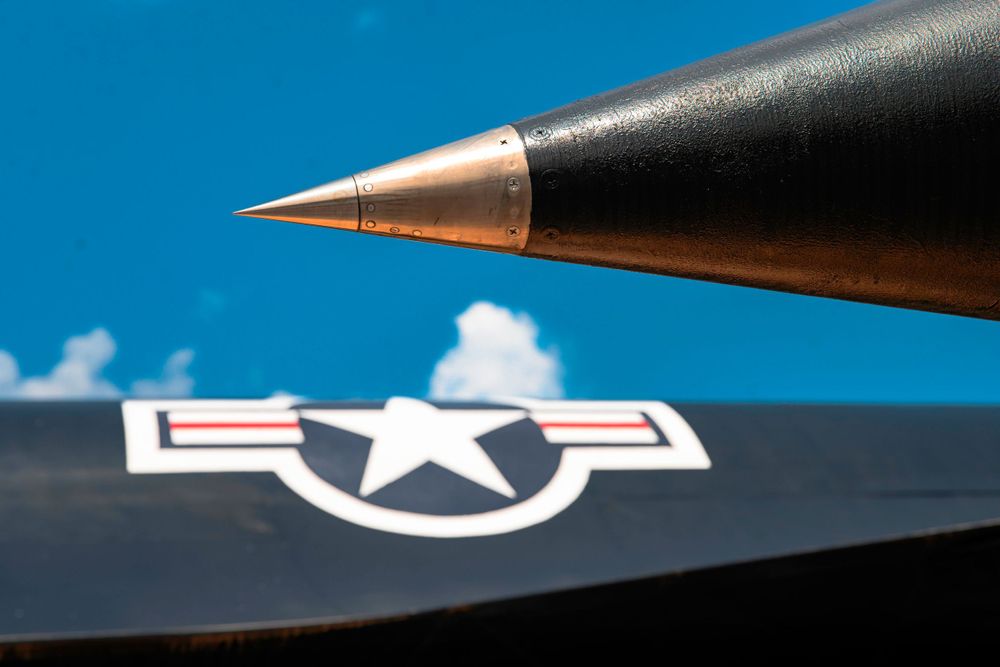 Close-up shot of a jet aircraft nose cone against blue sky with US Air Force insignia.