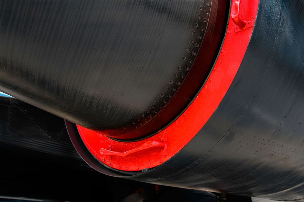 Detail shot of black aircraft fuselage with red trim component.