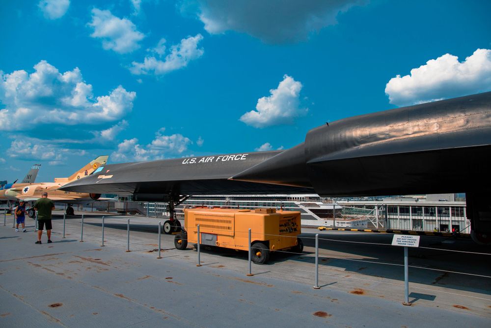 US Air Force SR-71 Blackbird on outdoor museum display with service equipment nearby.