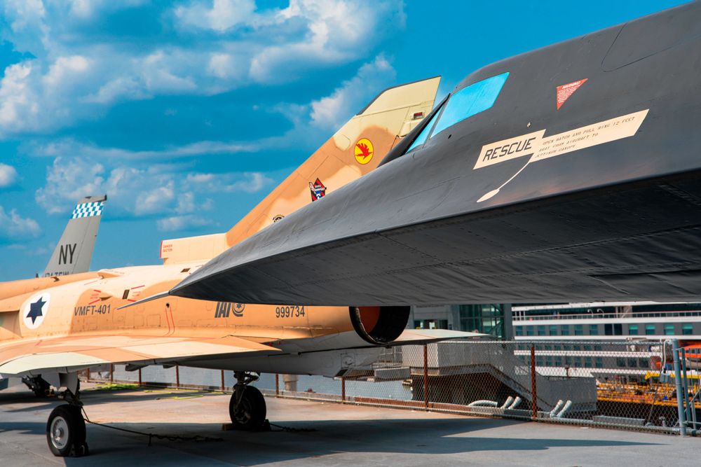 Military aircraft with desert camouflage paint scheme on outdoor display.