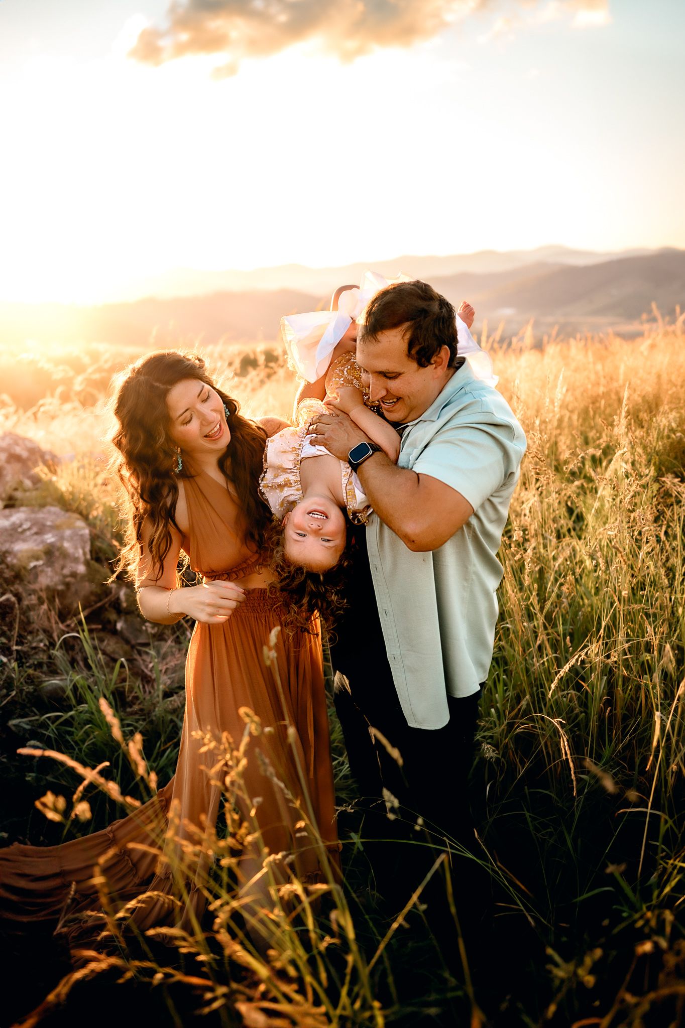 Playful family moment in tall grass during golden hour.