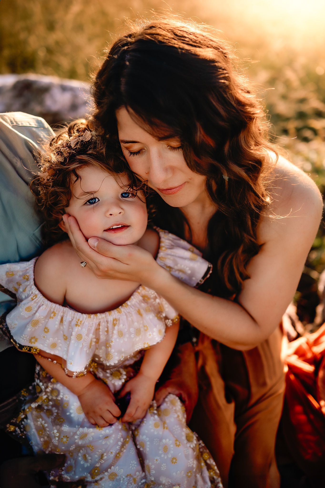 Sunset portrait of mother and child in golden field with warm lighting.