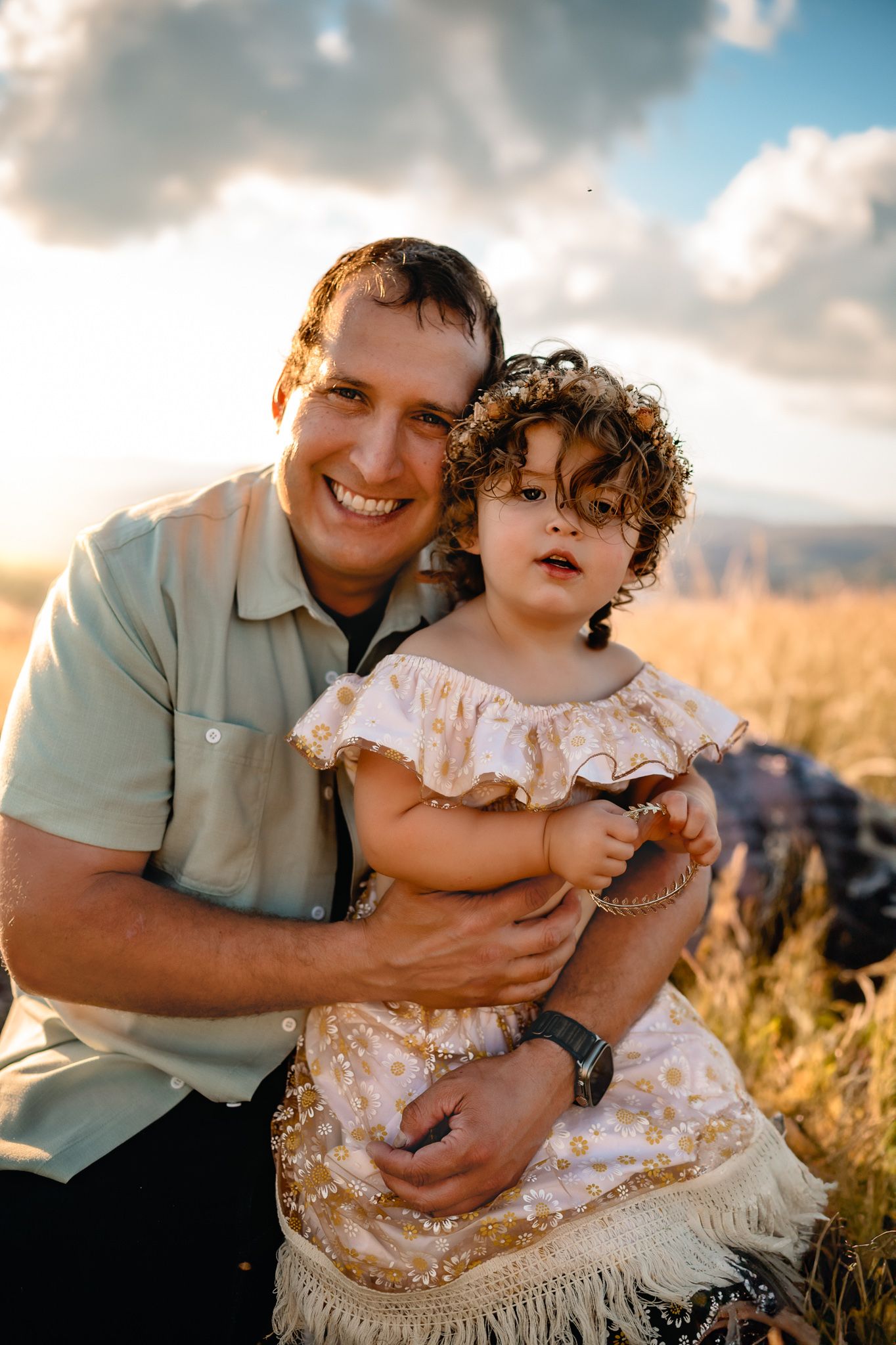 Joyful bonding moment in golden sunlight against cloudy sky.