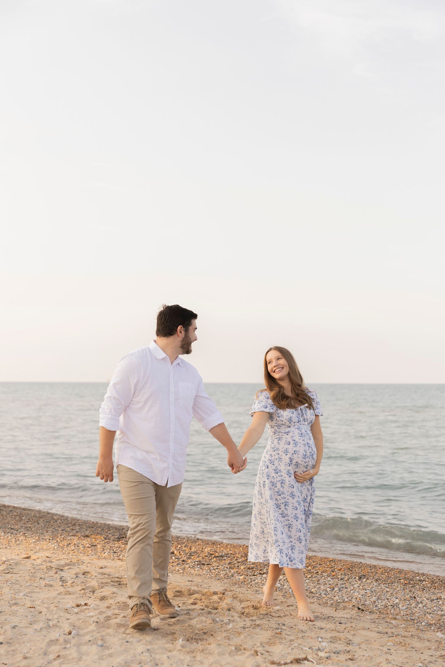 pregnant couple walking on the beach in lake huron