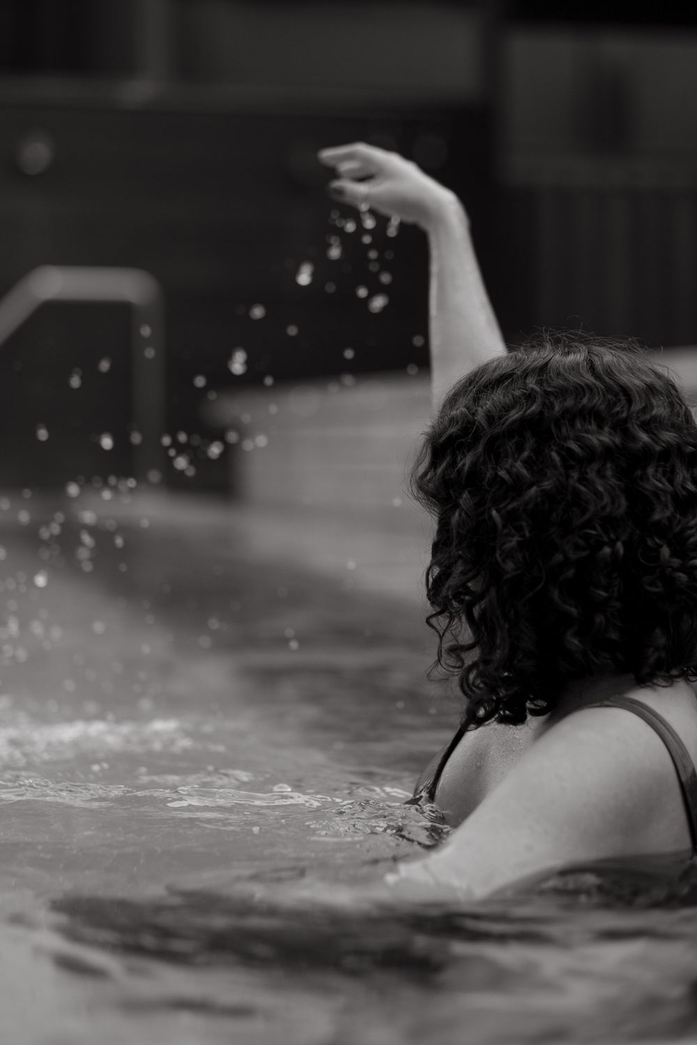 a woman splashing water in a pool while being captured by lifestyle photographer in Stockholm