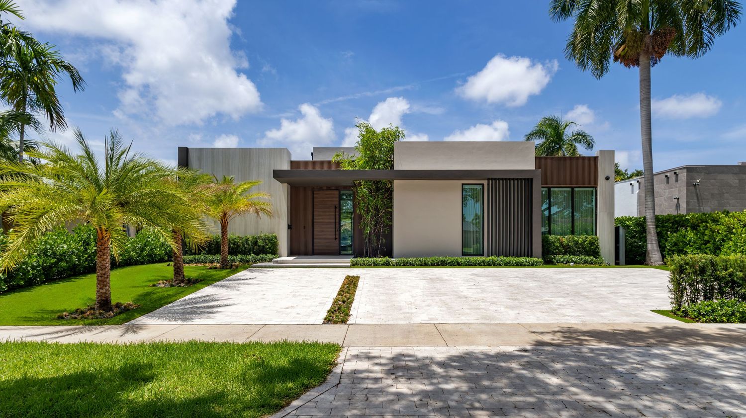 Contemporary residential architecture with landscaped driveways under blue sky.