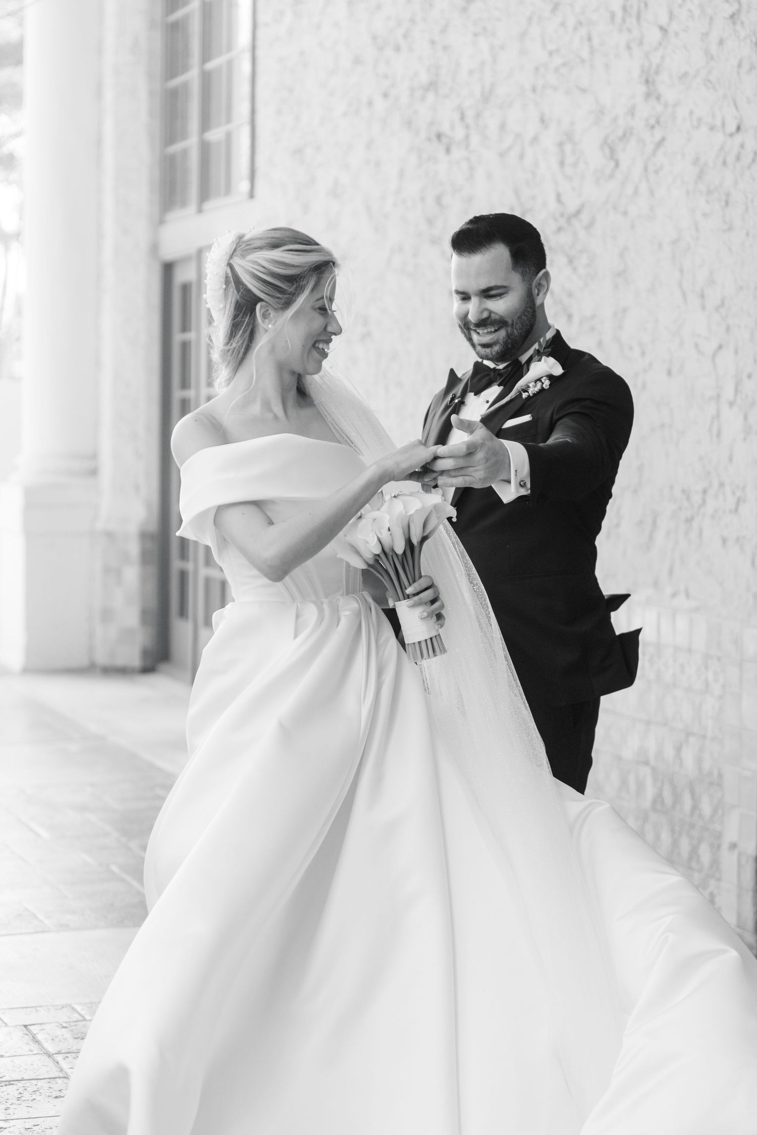 A joyful moment captured in black and white of a couple in wedding attire.