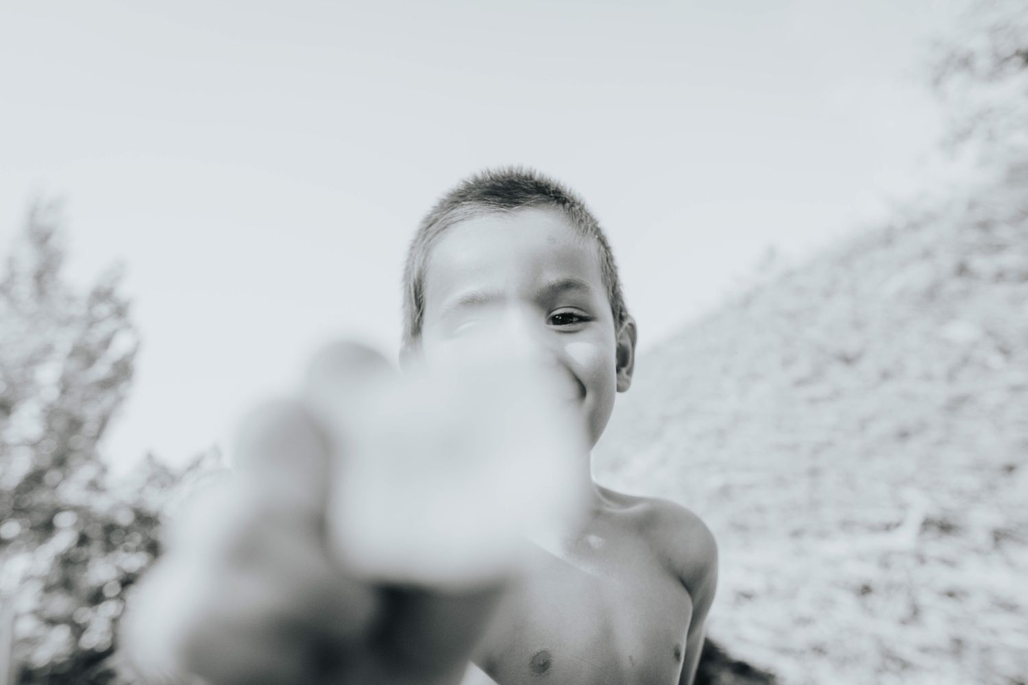 Person exhales a cloud of vapor while vaping outdoors against a blurred natural background.