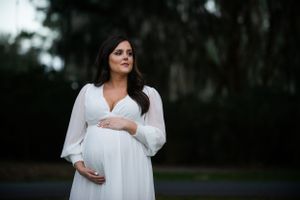 Maternity portrait in white flowing dress at dusk.