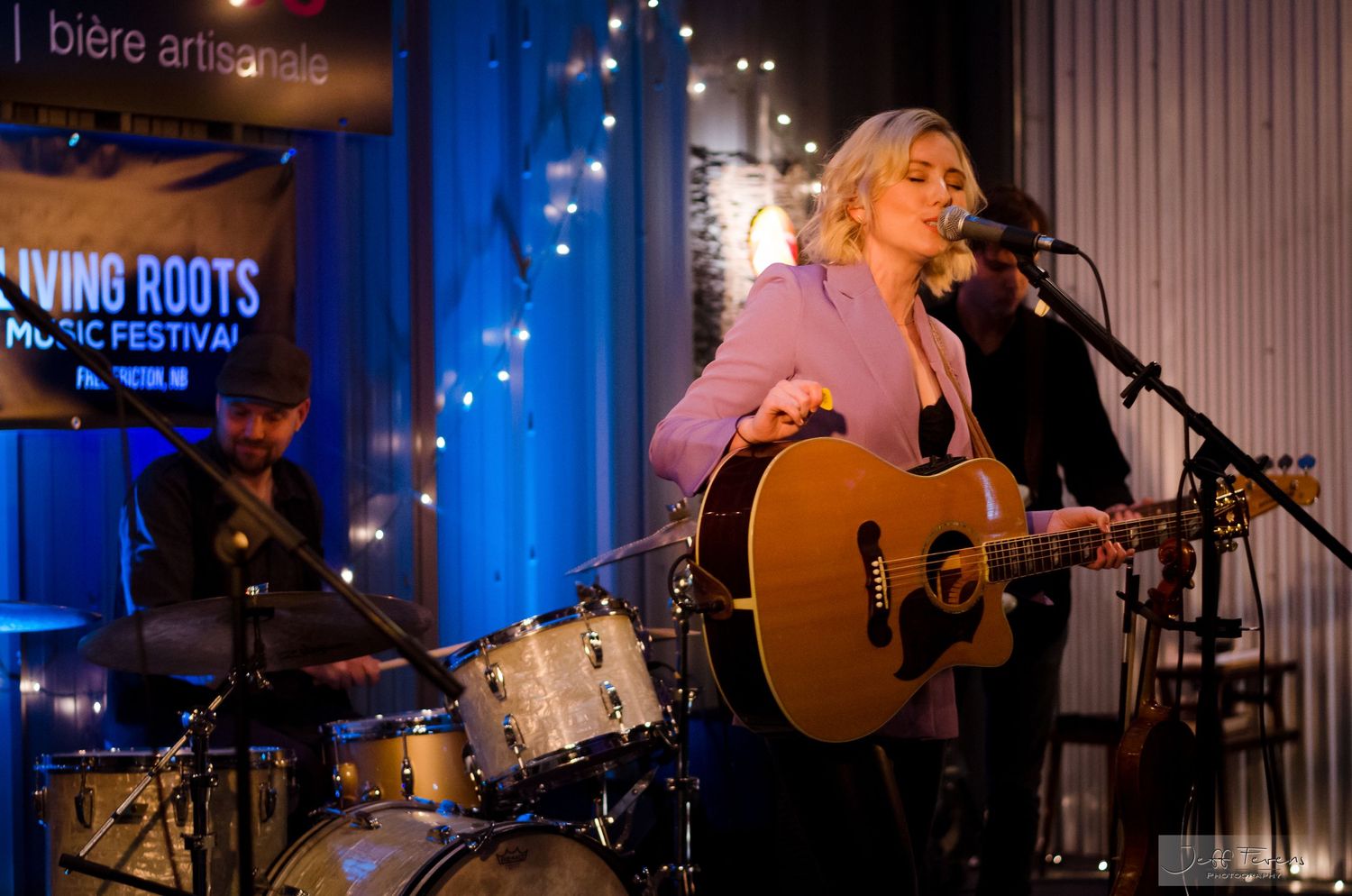 Americana female singer playing guitar on indoor stage.