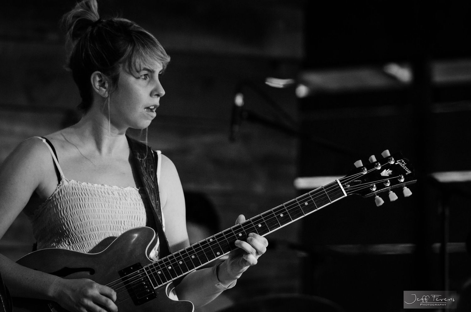 Female Folk rock guitar player on stage.