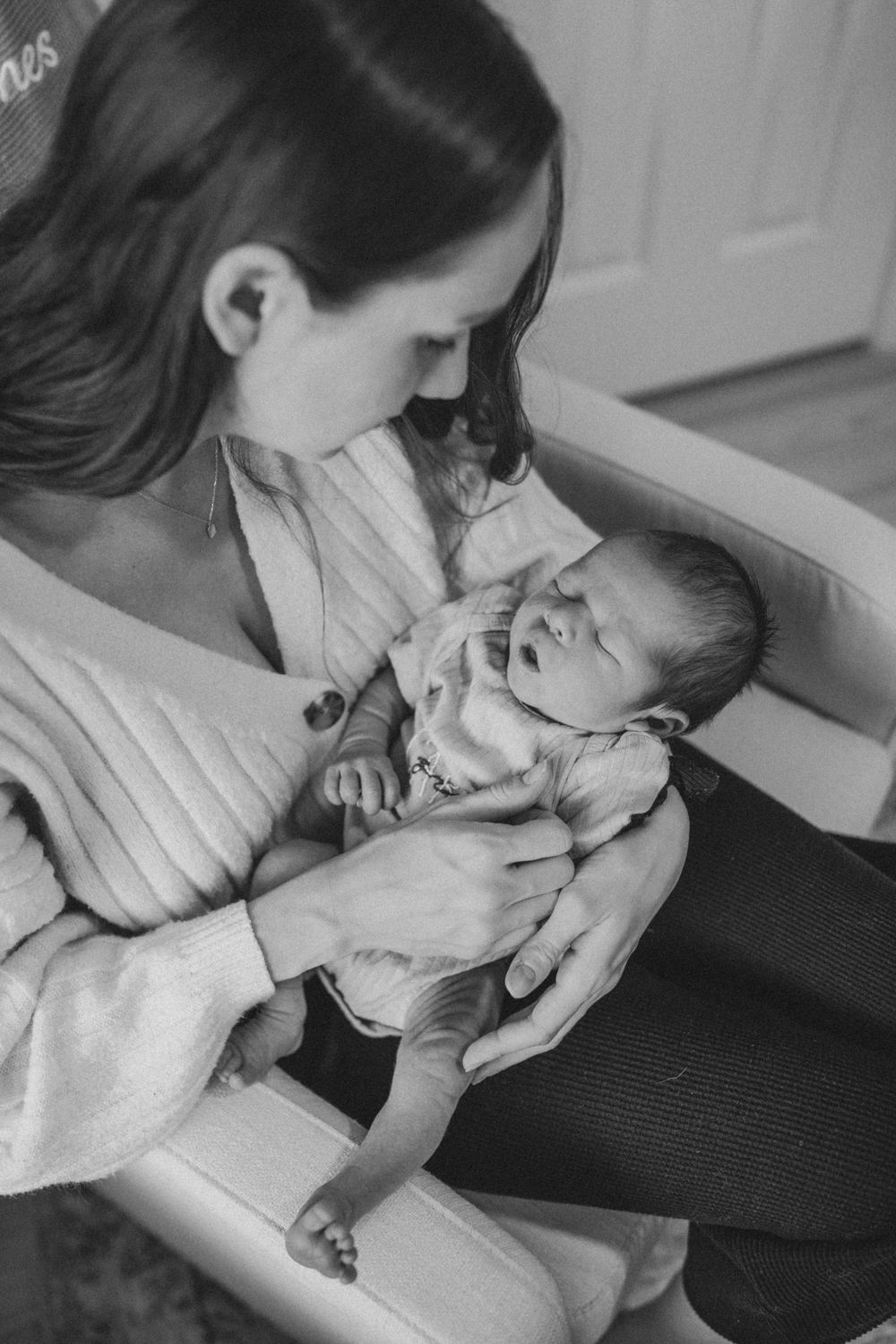 Tender black and white moment of mother cradling newborn baby.