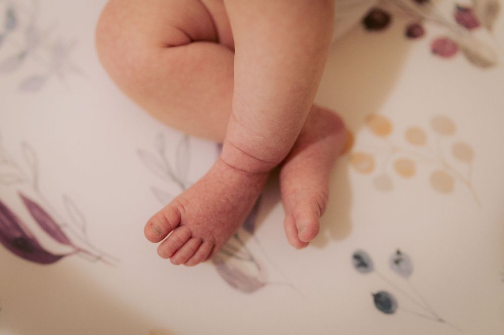 Close-up view of a tiny baby foot against a patterned background with soft colors.