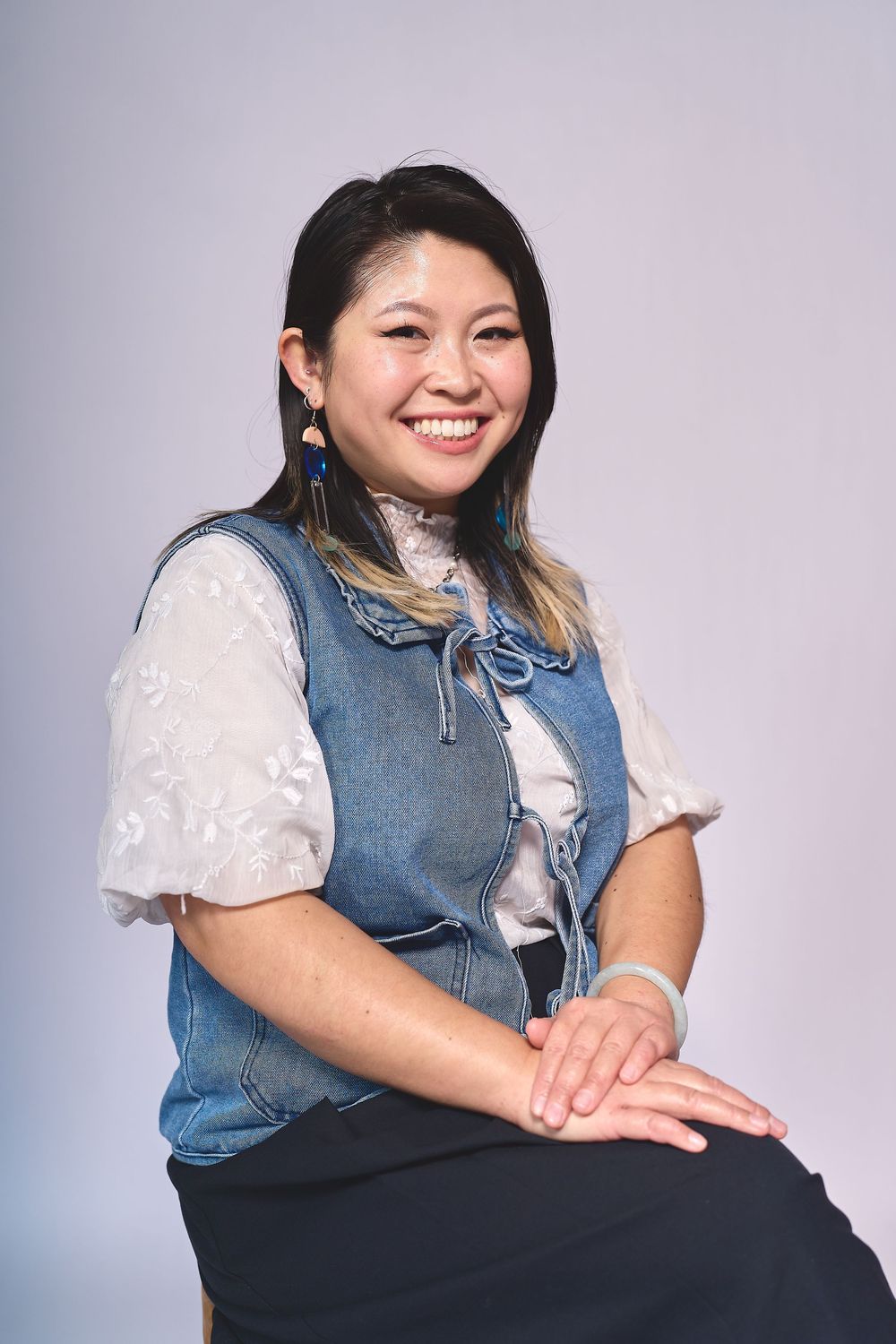 Smiling and seated woman posing for a headshot in a photography studio in Oakland, CA.