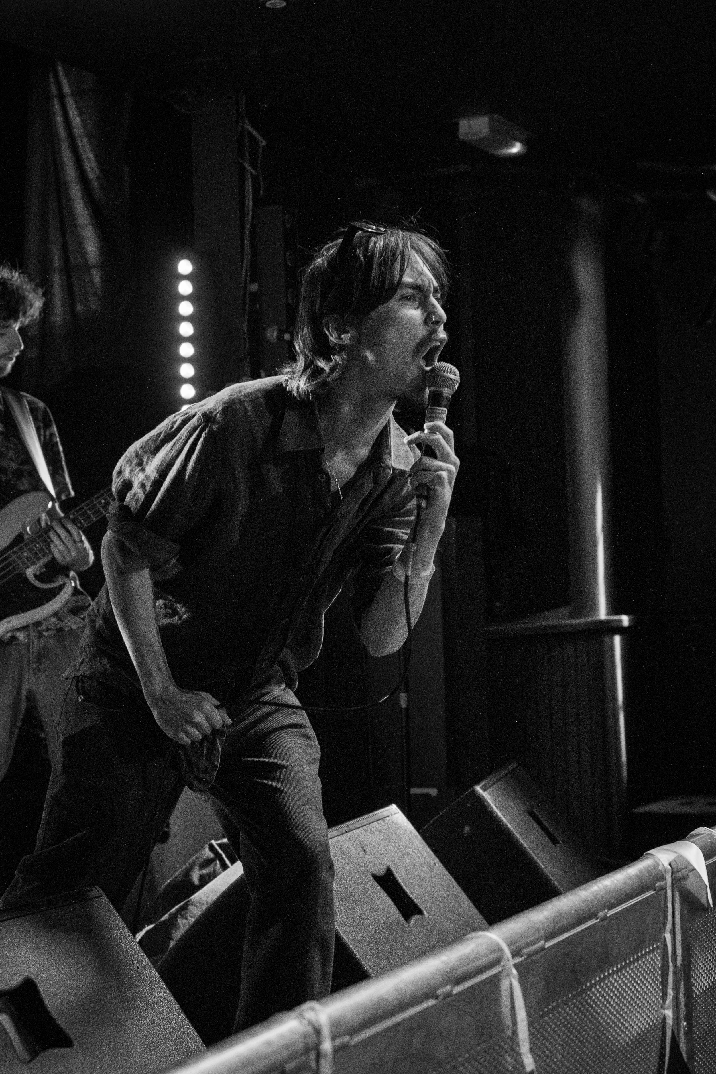 Vocalist passionately performs on stage in dramatic black and white lighting.